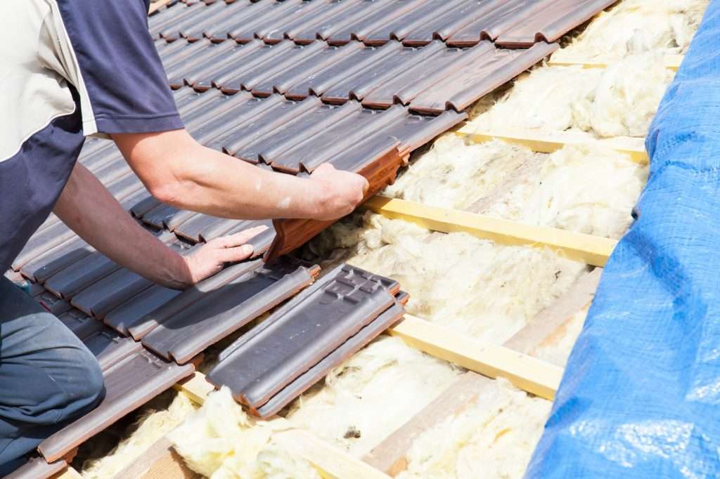Roofer laying tiles on roof
